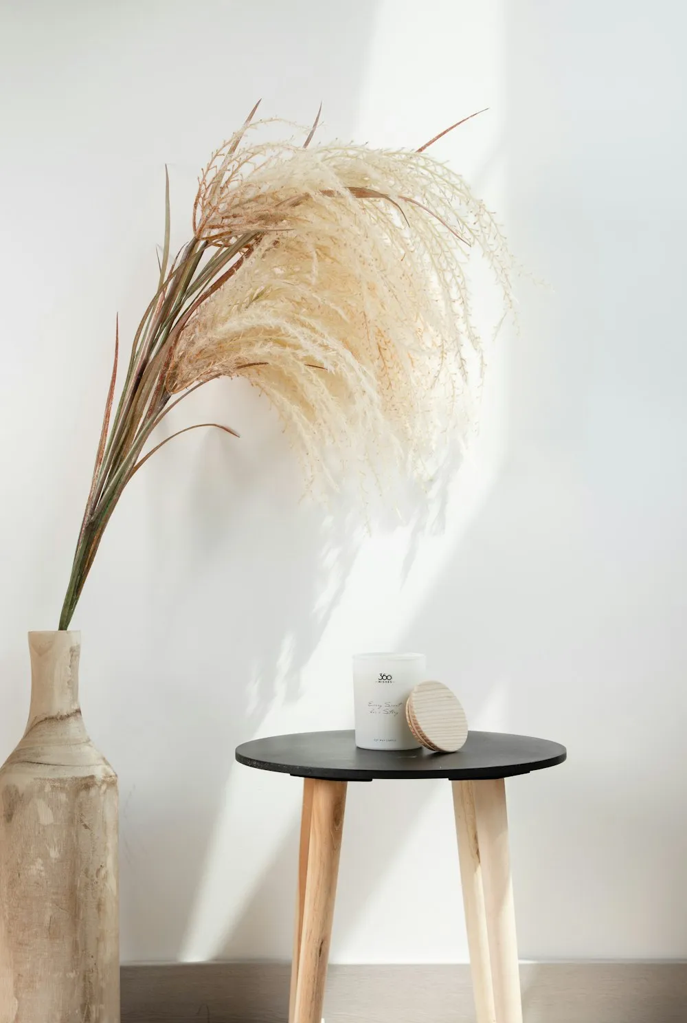 Herbe de la pampa dans un vase, près d’un tabouret en bois