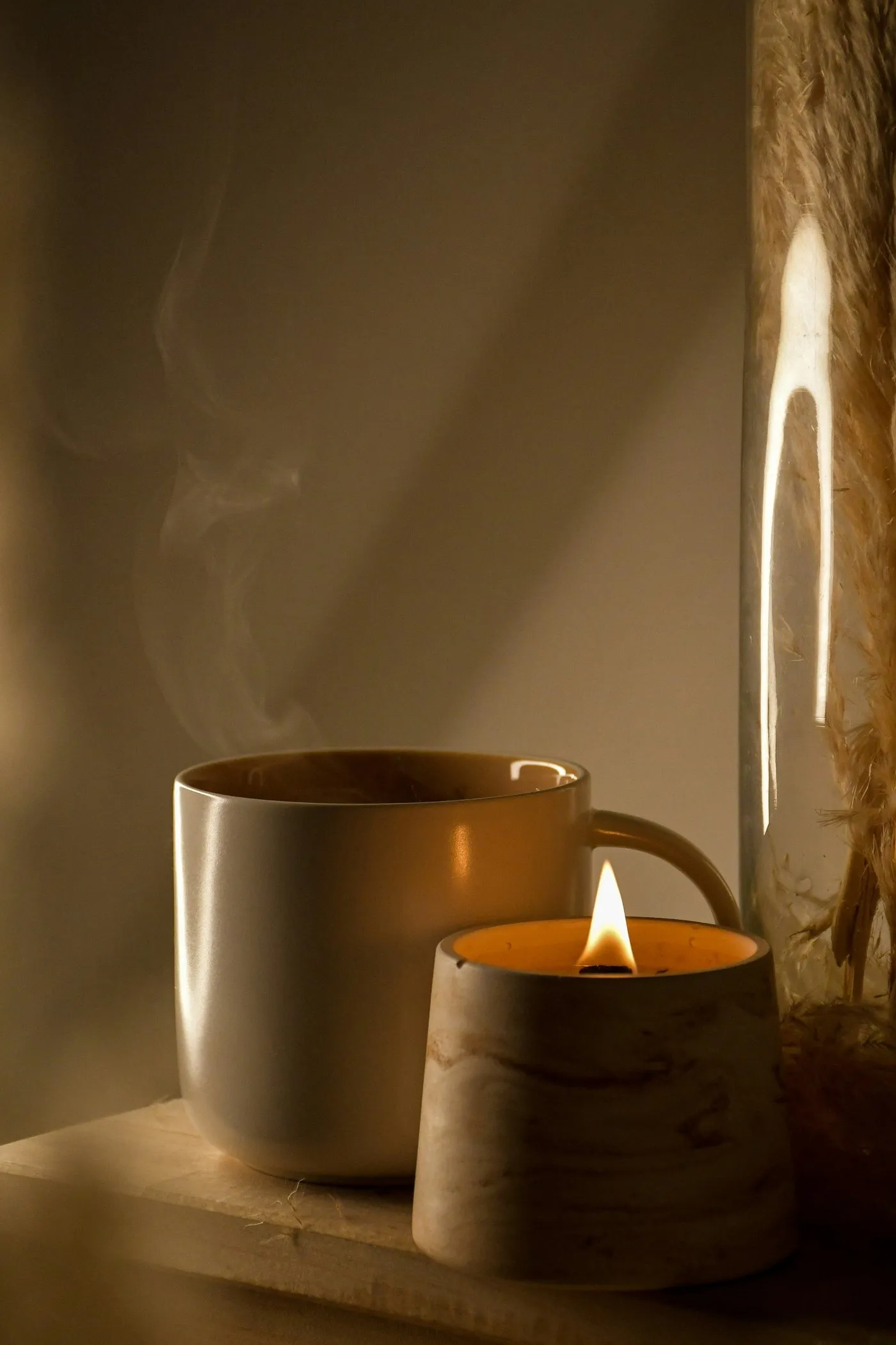 Tasse fumante et bougie allumée dans une lumière chaude